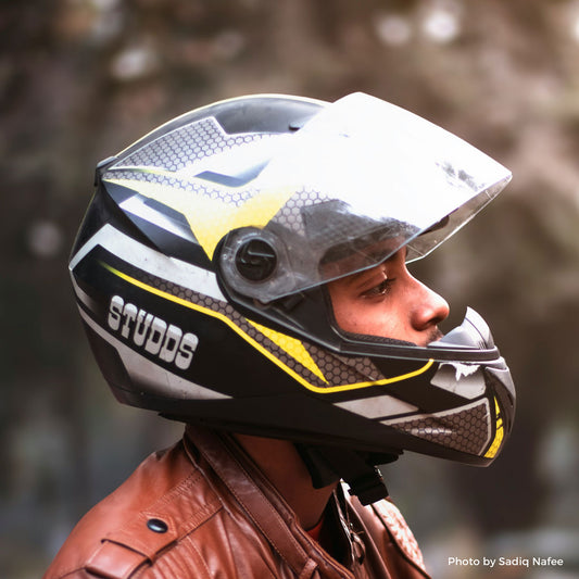 Young man wearing a brown leather jacket and a motorcycle helmet