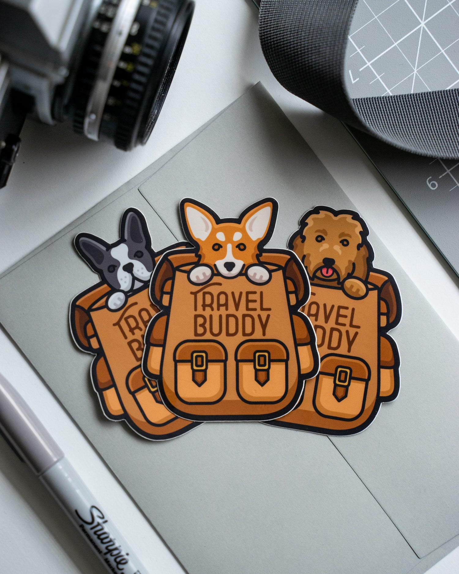 Photo by Done By Alex on Unsplash. Three die-cut stickers of dogs in backpacks