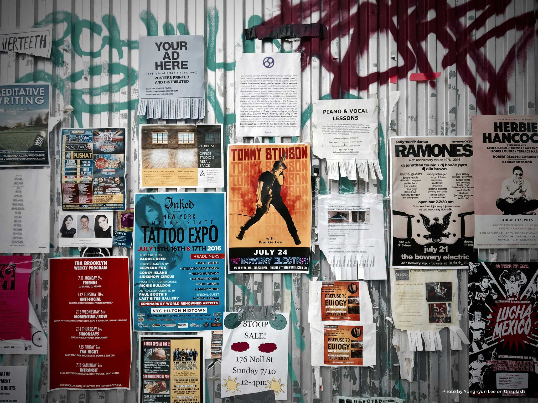 Corrugated metal wall covered in a variety of posters